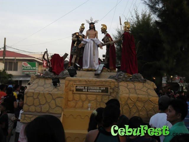 A Holy Week float carrying life-size statues of Christ and Roman soldiers, moving through a crowd on a Bantayan street